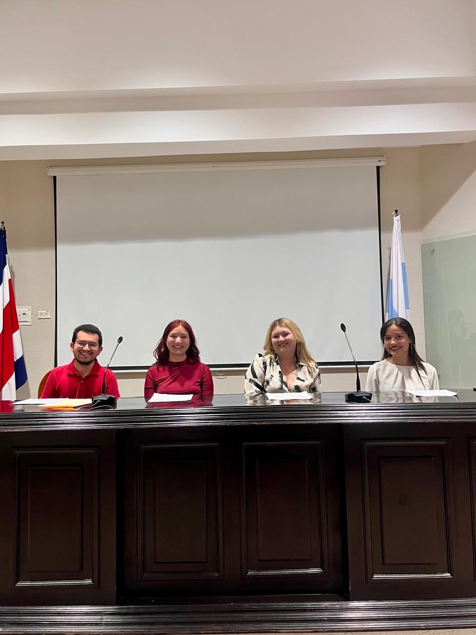 Panel de expositoras y expositores en la mesa directiva del auditorio